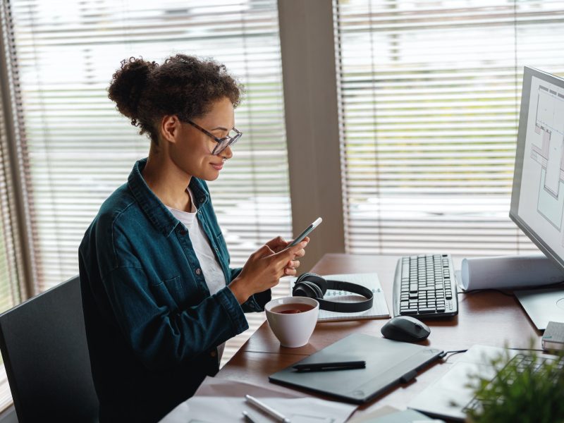 smiling-woman-interior-designer-holding-smartphone-during-break-at-home-office-freelance-concept.jpg